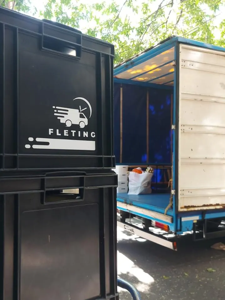 Cajones con el logo de Fleting listos junto al camión de mudanza