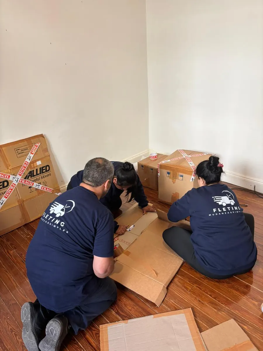 Equipo de Fleting embalando pertenencias en el piso de un ambiente