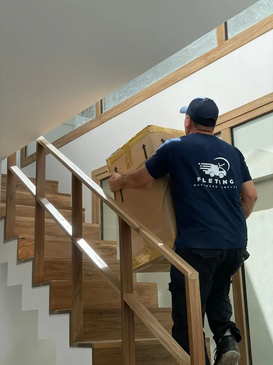 Operario de Fleting subiendo una caja por la escalera de una vivienda