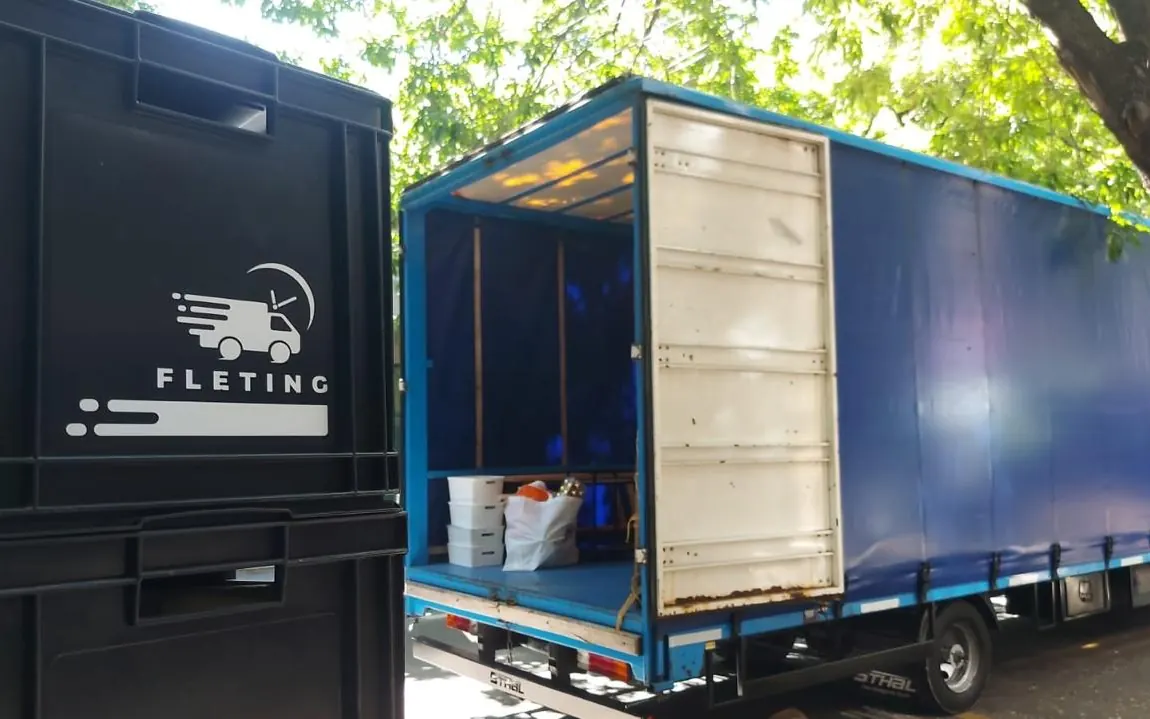 Cajón con el logo de Fleting junto a un camión de mudanza en una operación real